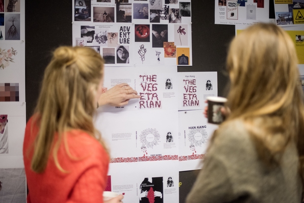 Foto av tre grafisk design studenter som arbeider med en logo på pcene sine.