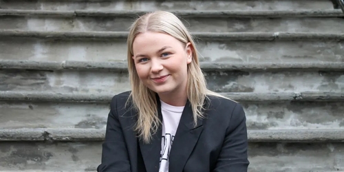 En kvinnelig student ser mot kamera og smiler. Foto